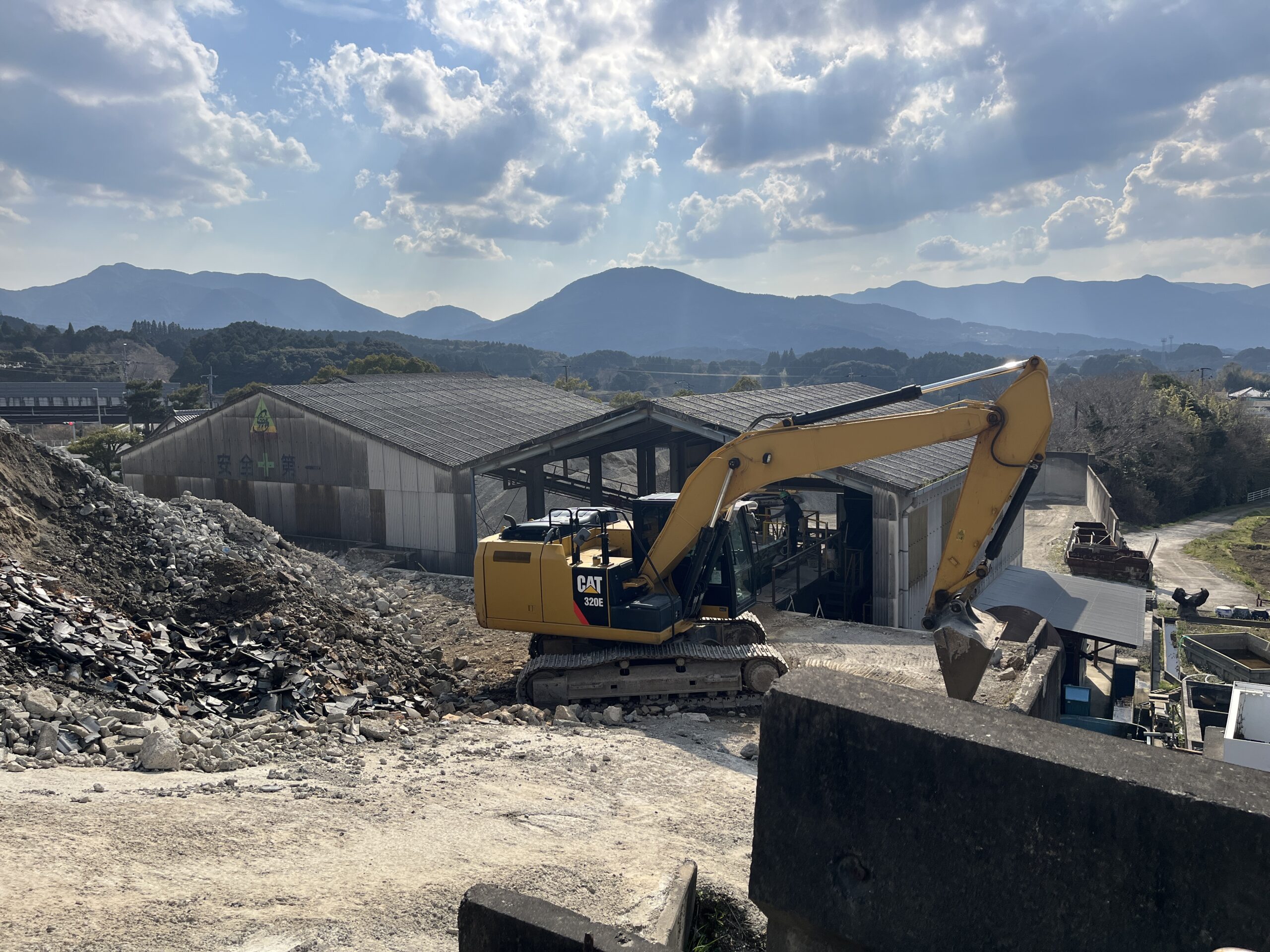 CAT 320E油圧ショベルがリサイクルクリーンセンターのヤードで廃材の集積・搬送作業を行っている全景